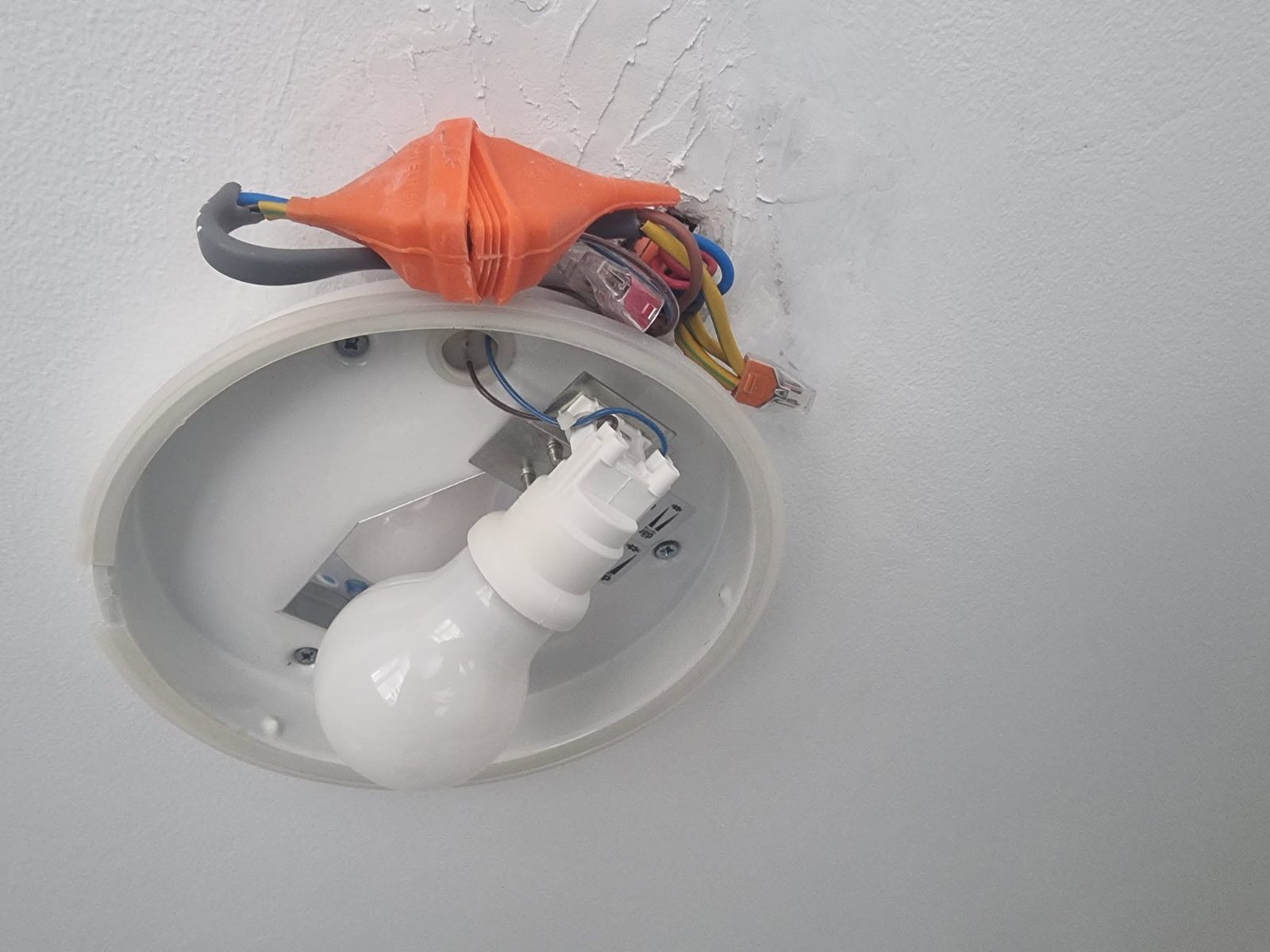 A bathroom light fitting with cables left outside the fitting