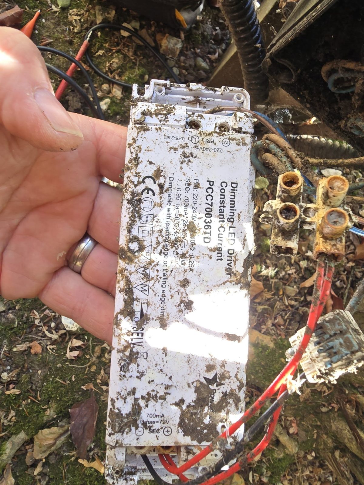 A muddy LED driver dug out of a garden with corroded connector blocks
