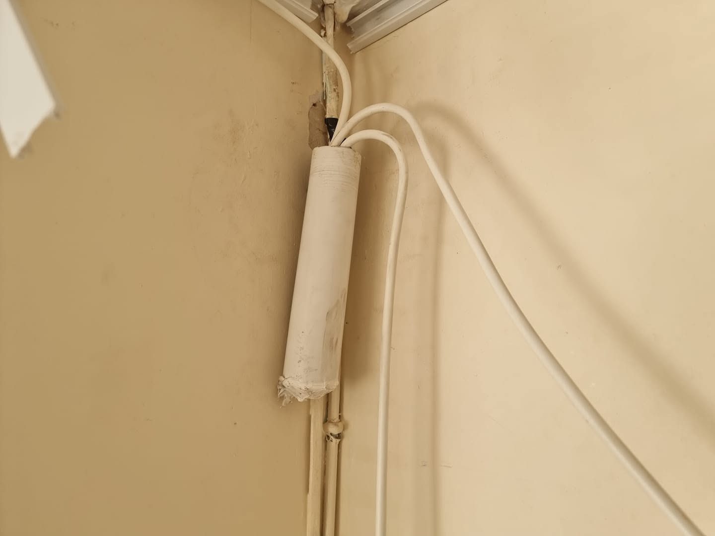 A cable joint hidden inside a piece of waste pipe on a wall