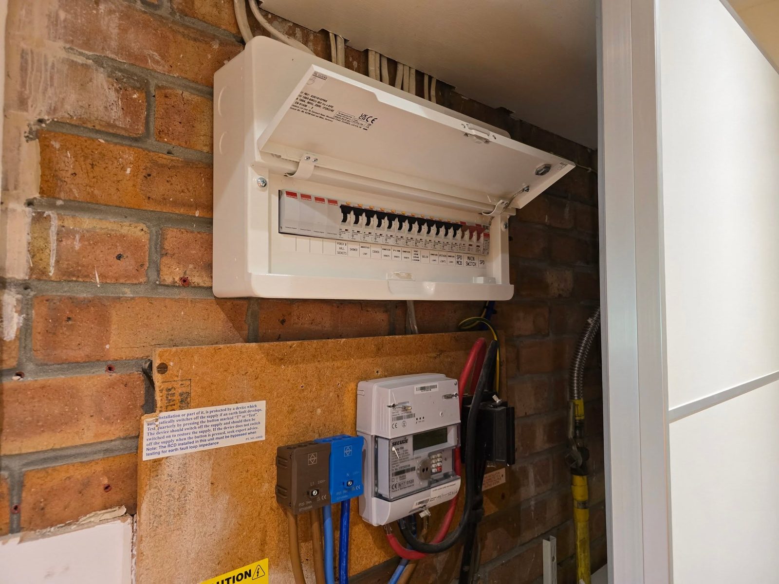 A new consumer unit above the meter and isolator on a brick wall
