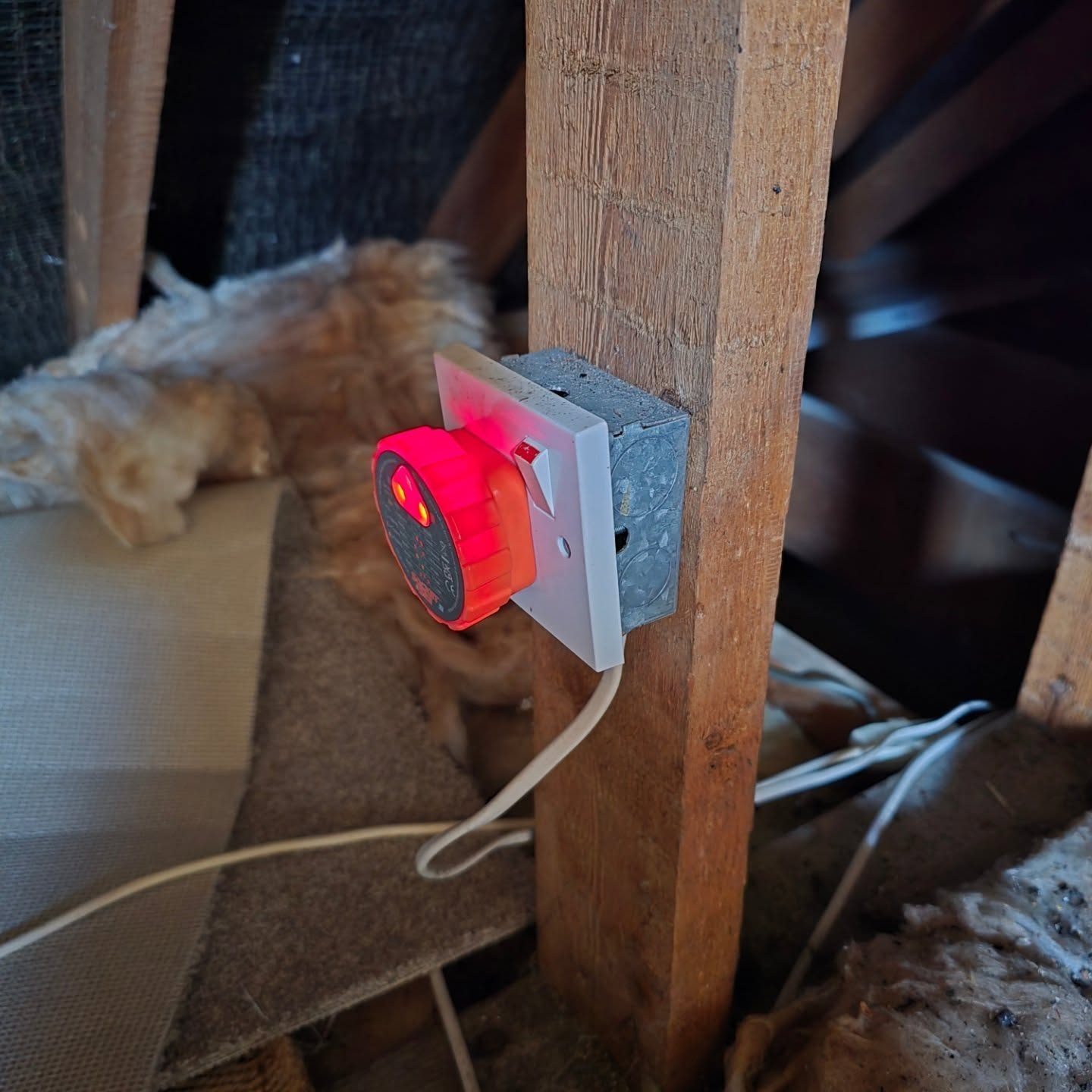 A socket tester plugged into a socket in a loft